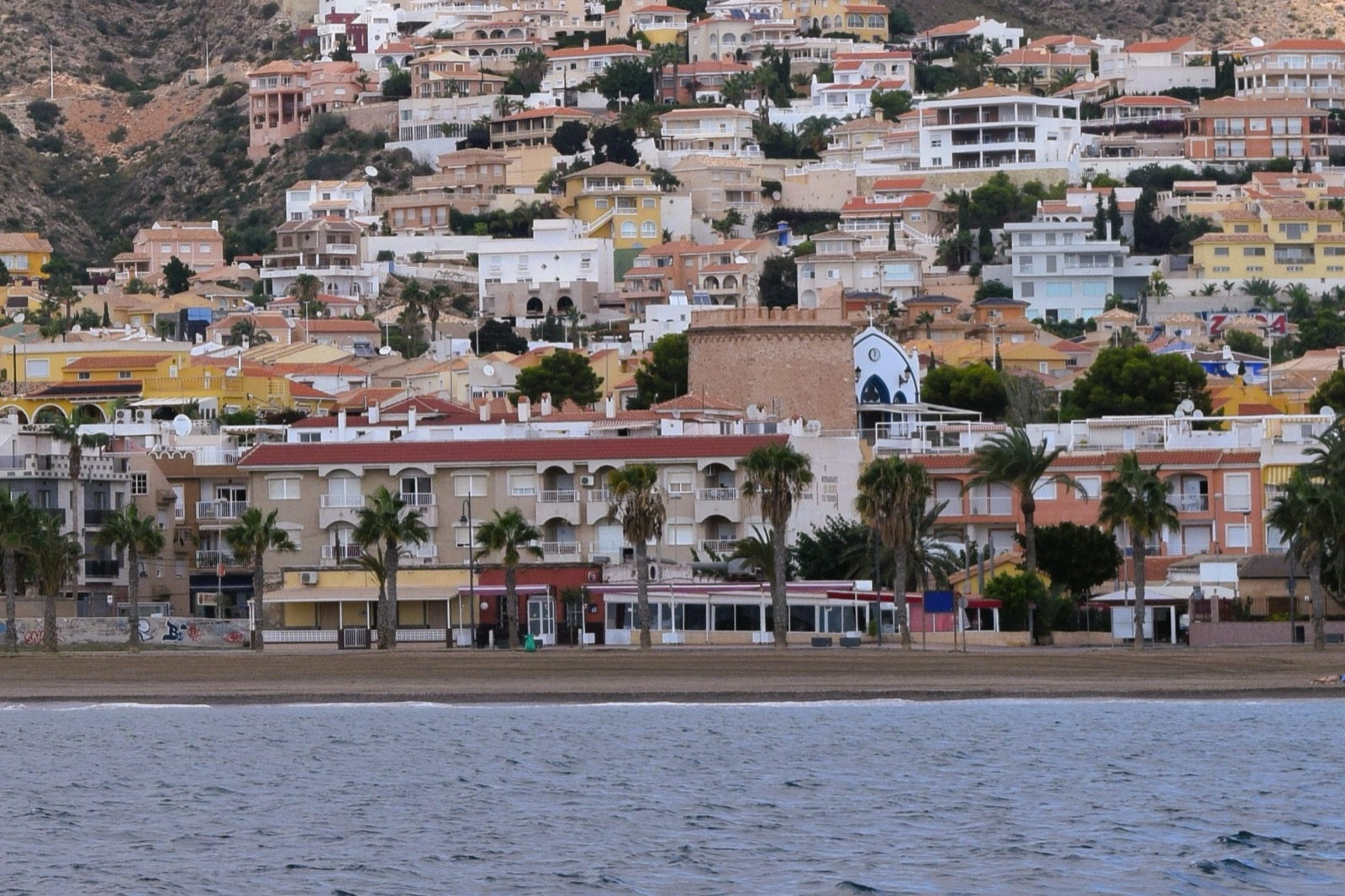 Bolnuevo seafront and beach viewed from the sea, with the chapel and watchtower