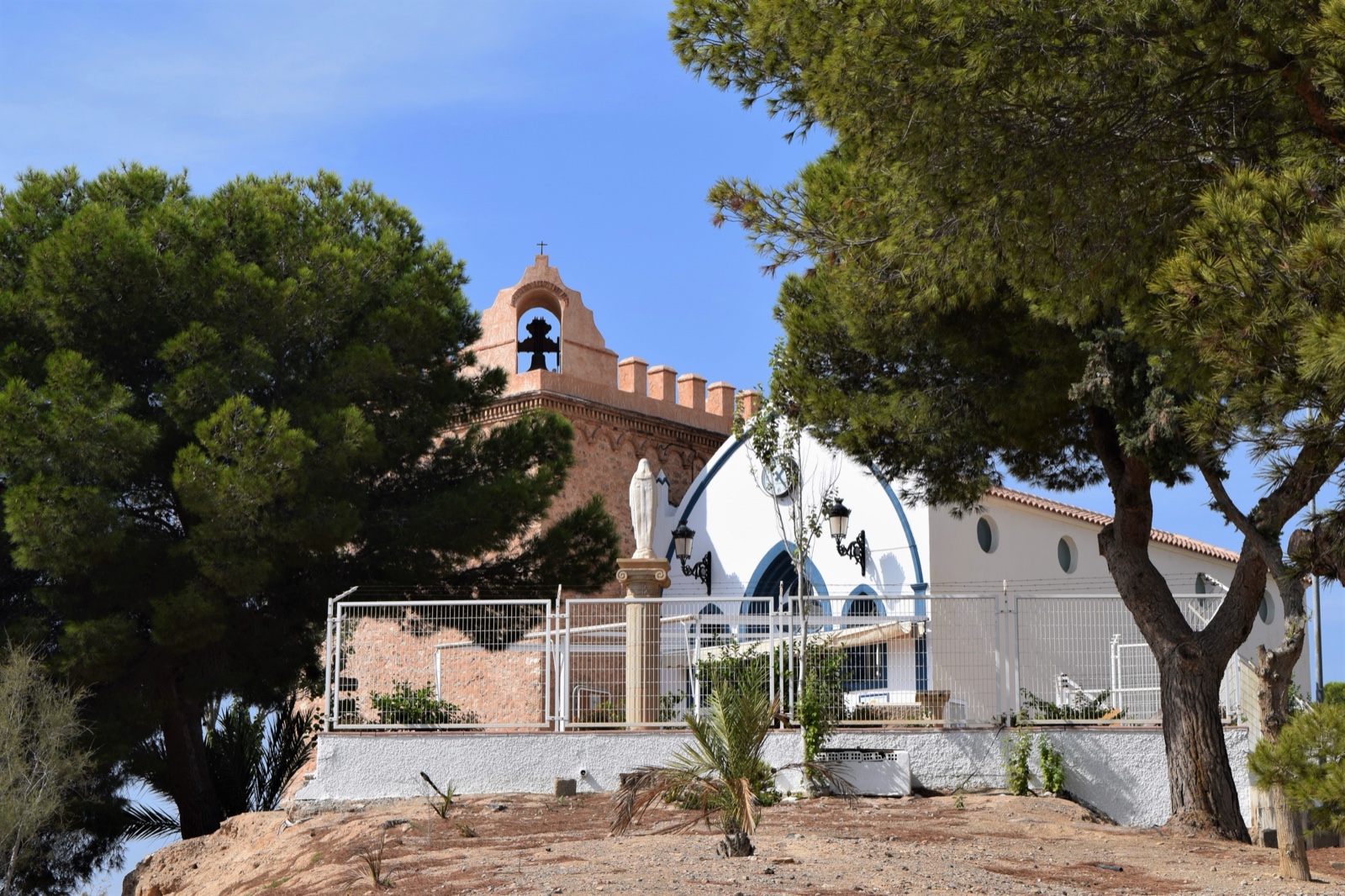 The Ermita de Bolnuevo chapel with its bell tower, framed by pines