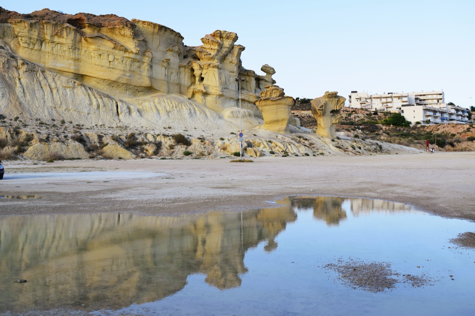 The golden Gredas mushroom rock formations at Bolnuevo reflected in a rainwater pool