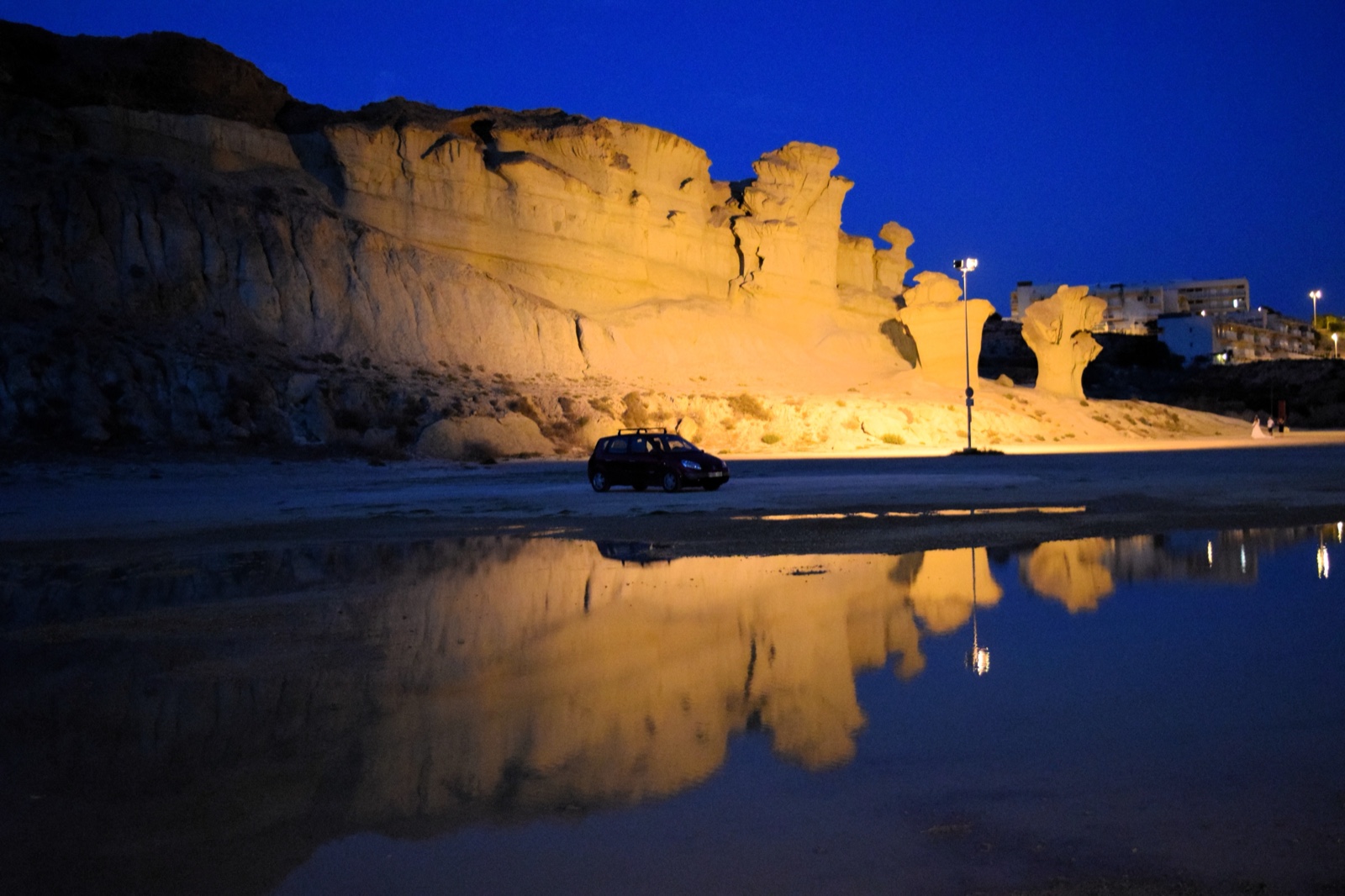 The floodlit Gredas cliffs at Bolnuevo mirrored in a rainwater pool at night
