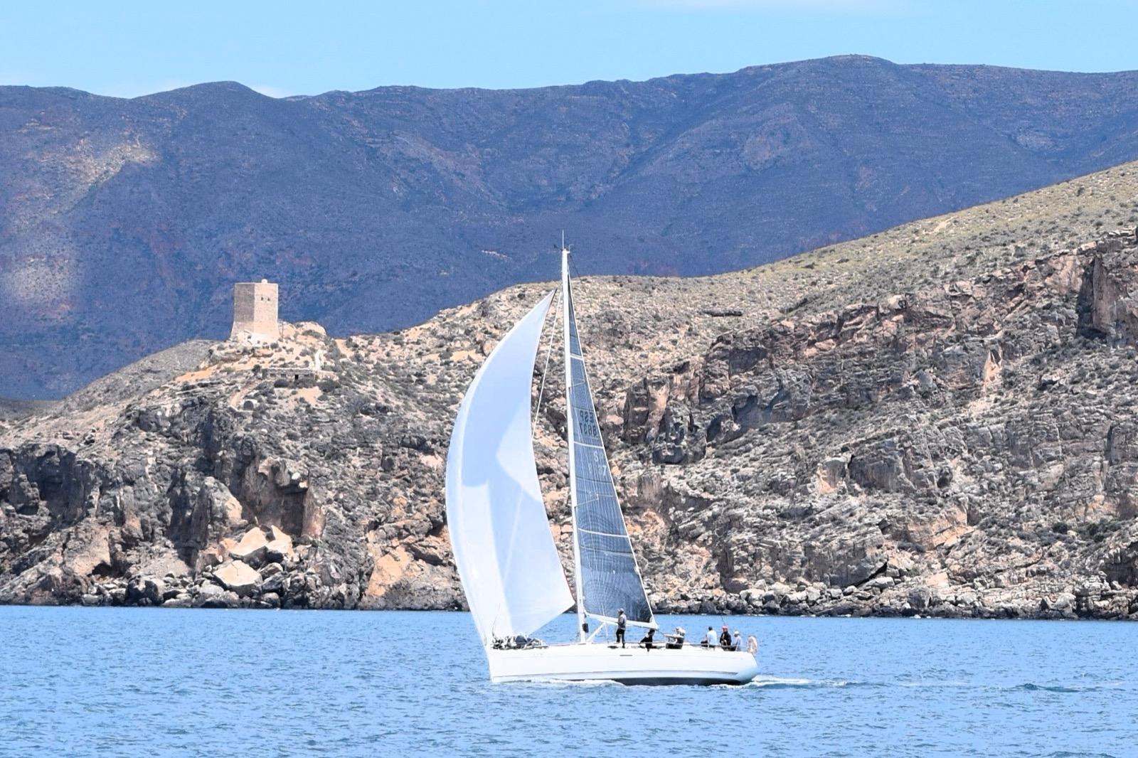 A yacht sailing off La Azohía with the old coastal watchtower on the headland