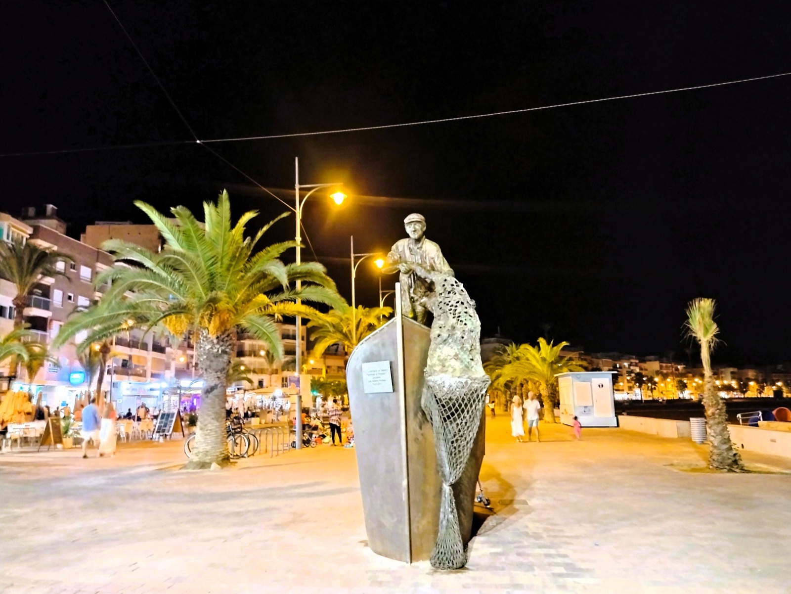 The bronze fisherman statue on the Puerto de Mazarrón promenade at night