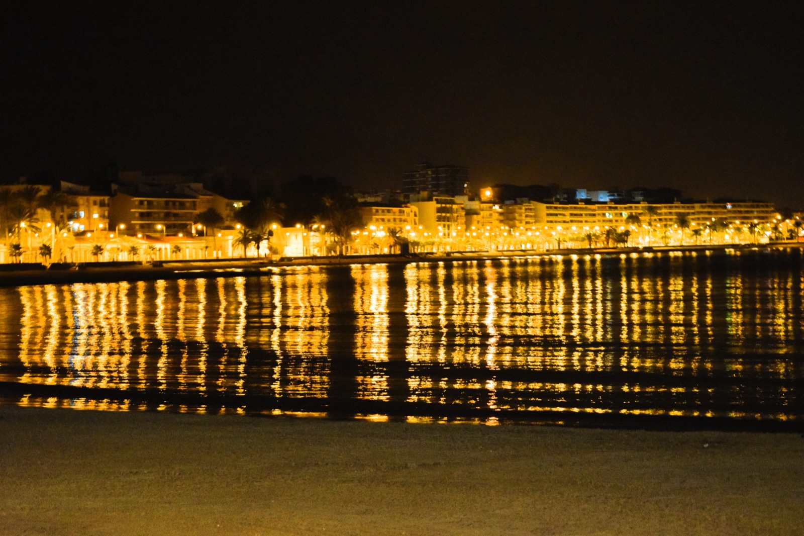 The Puerto de Mazarron seafront lights reflected across the bay at night