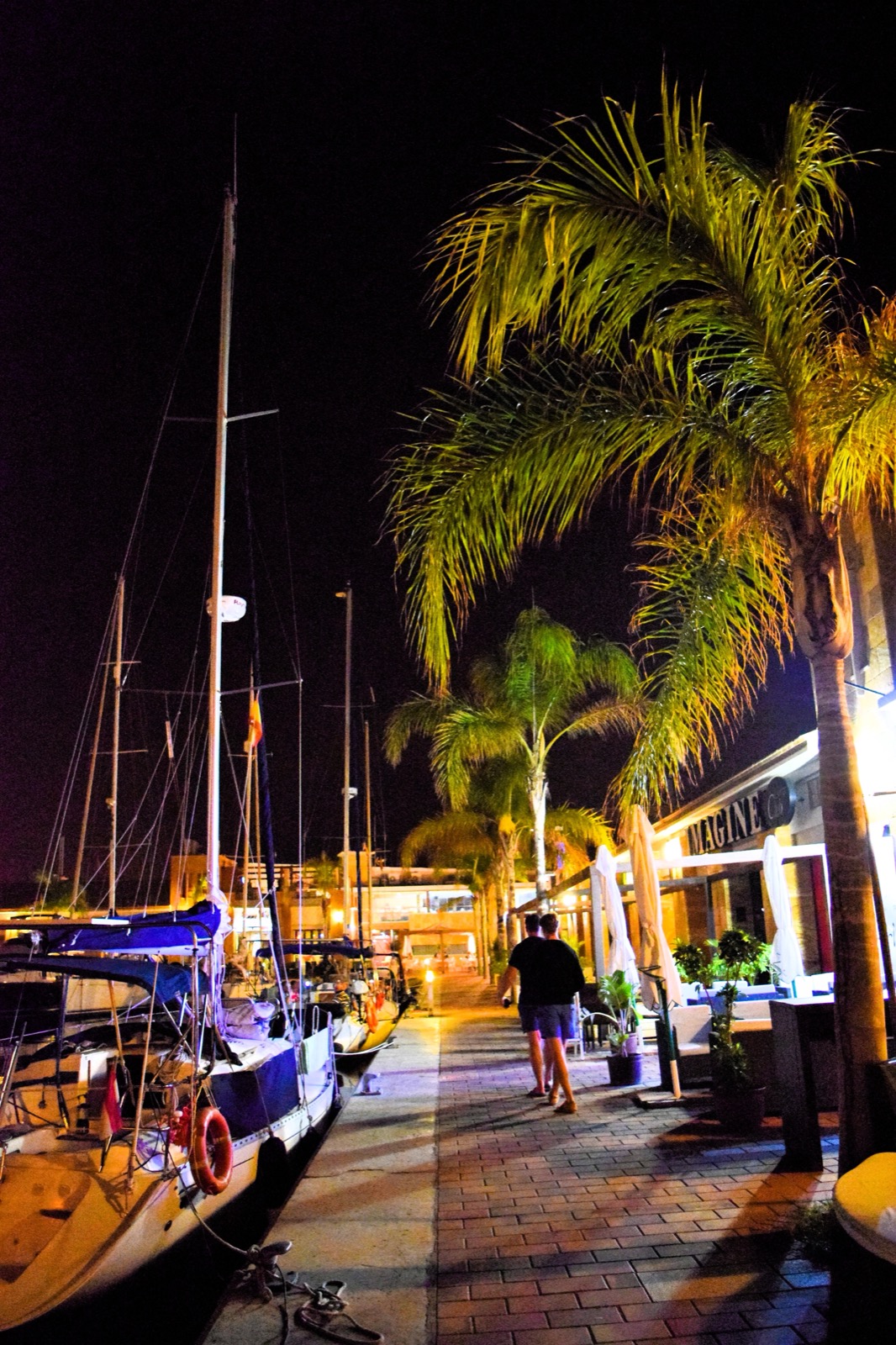 An evening stroll along the marina promenade at Puerto de Mazarron, with moored yachts and lit palm trees