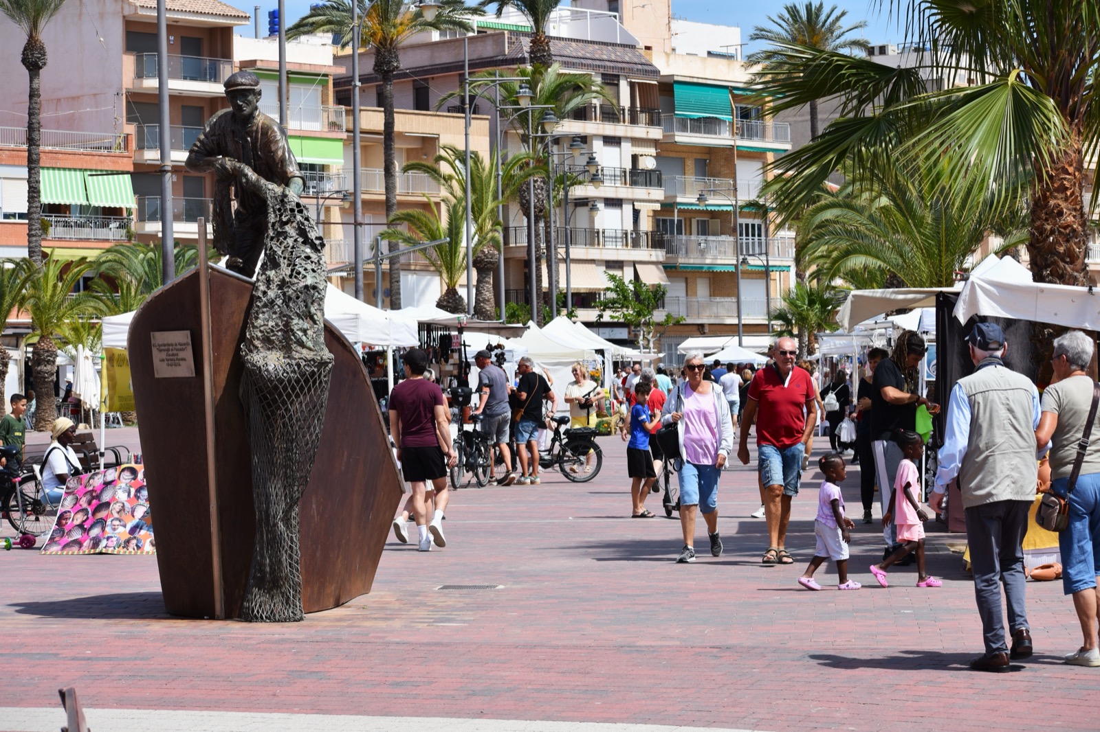 Market day on the Puerto de Mazarron seafront with the fisherman statue on the paseo