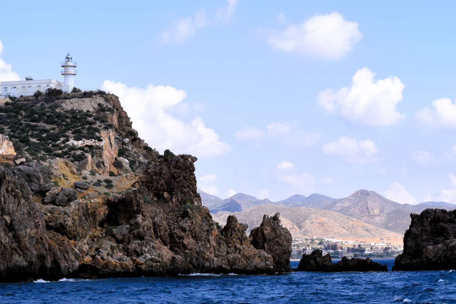 The lighthouse headland and rocky coast at Puerto de Mazarron from the sea