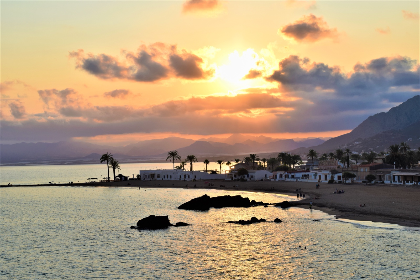 Golden sunset over the bay at Playa de Nares with palms and mountains