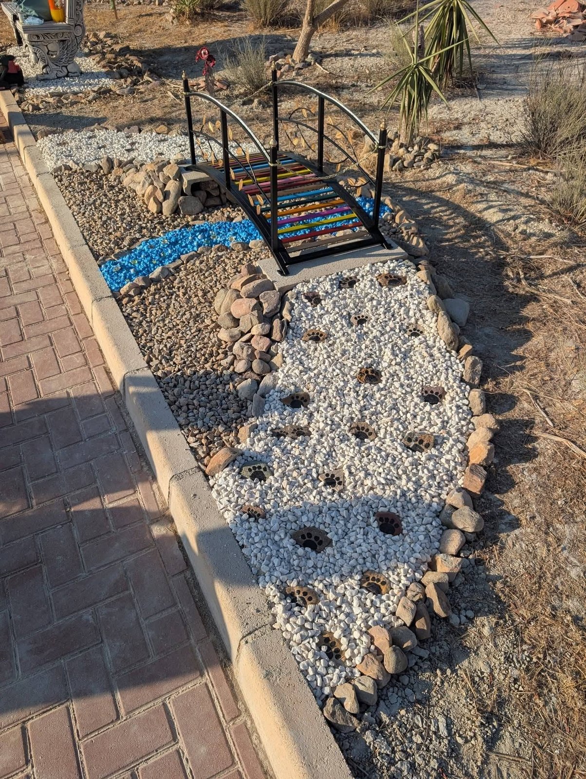 The rainbow bridge over a stream of blue glass with paw print stones