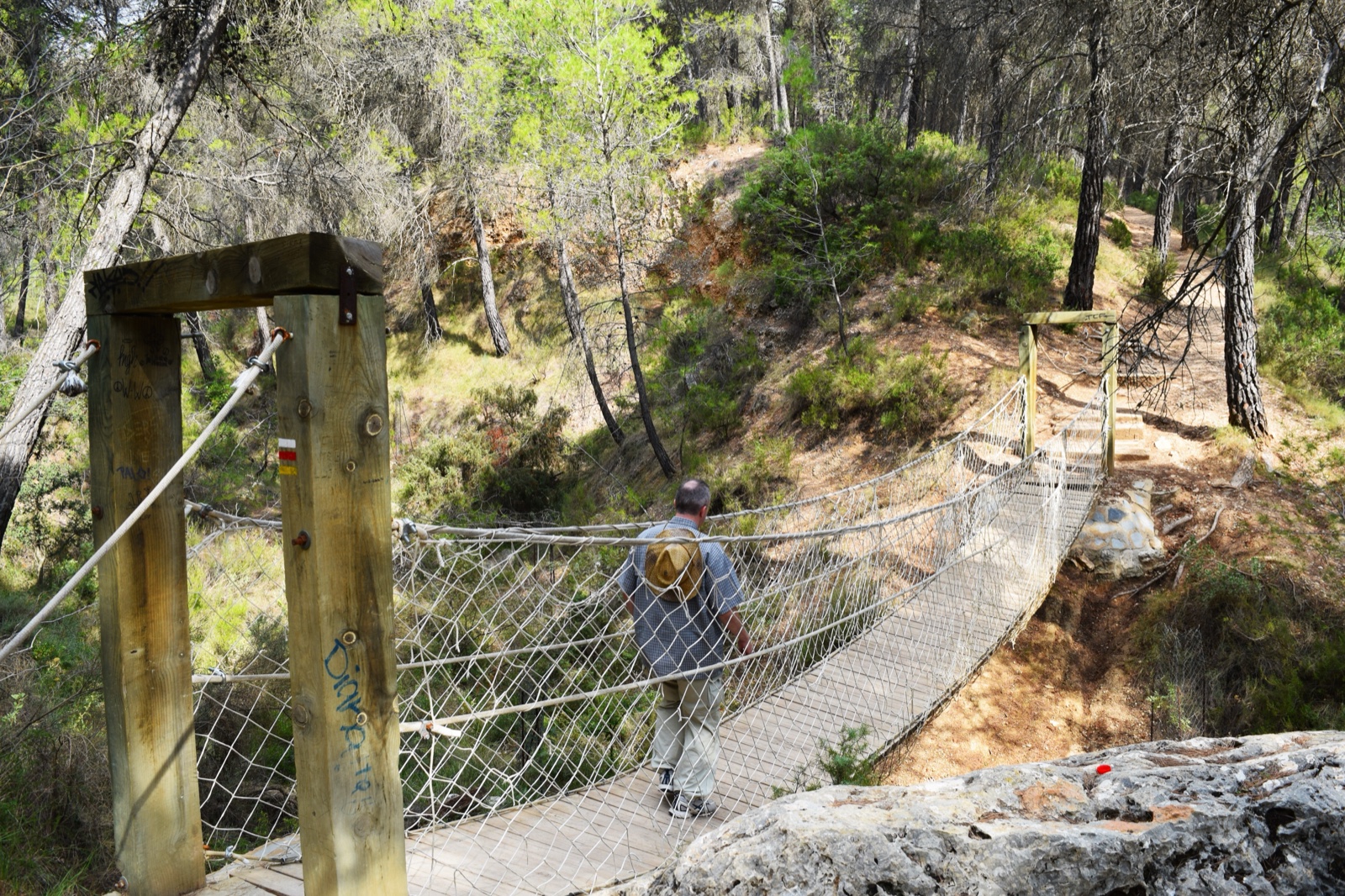 Hiker crossing a rope suspension bridge on a trail, Sierra Espuna