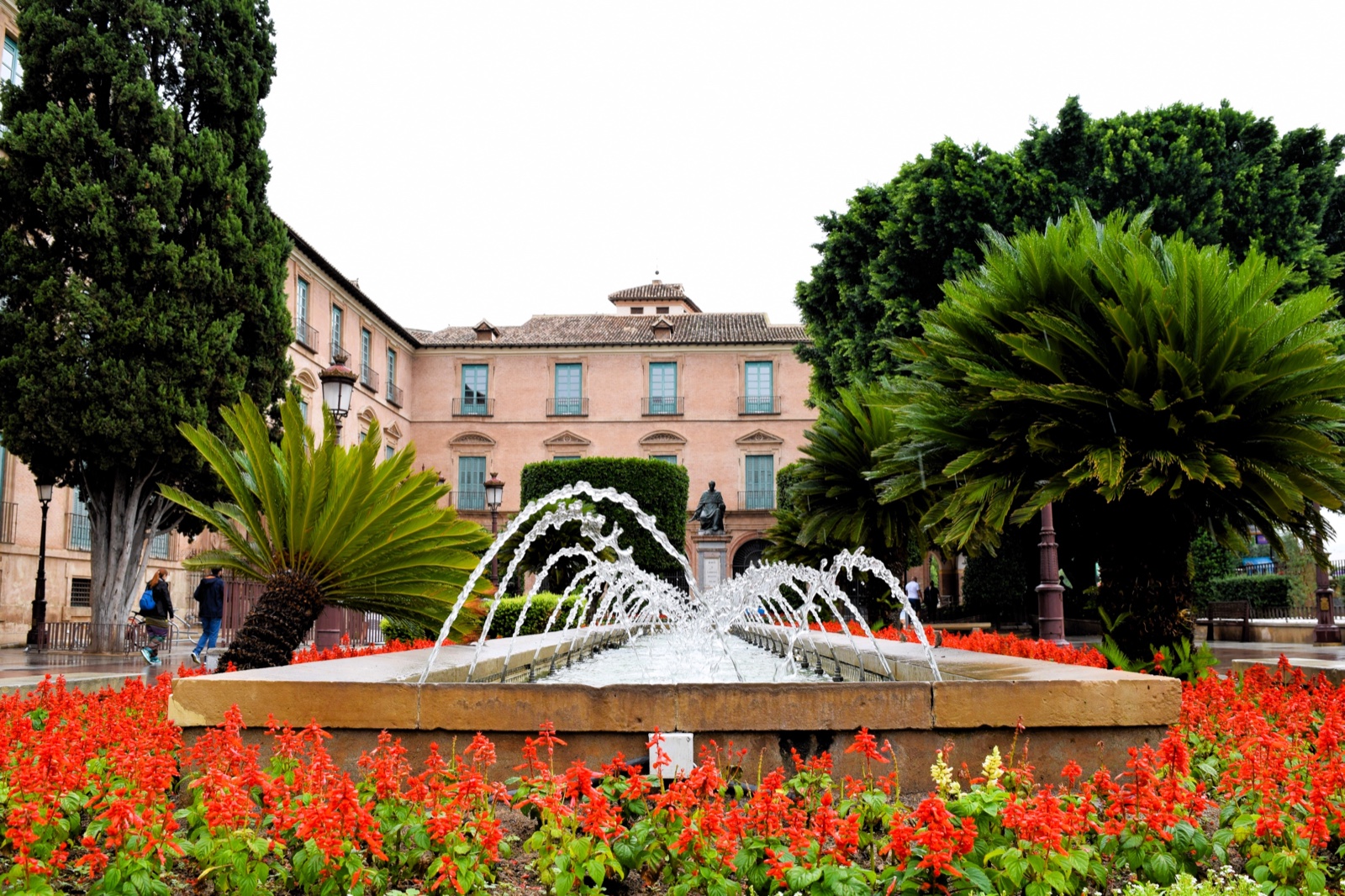 Fountain and red salvia flowers in front of the Bishop's Palace, Murcia City
