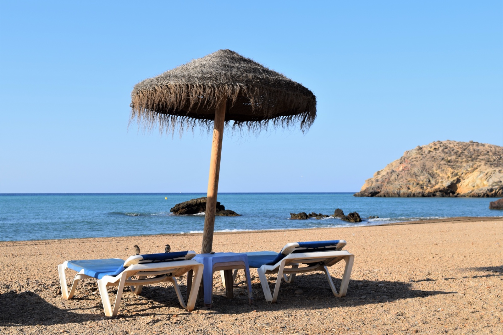 A thatched parasol and sun loungers on the beach at Playa de Nares