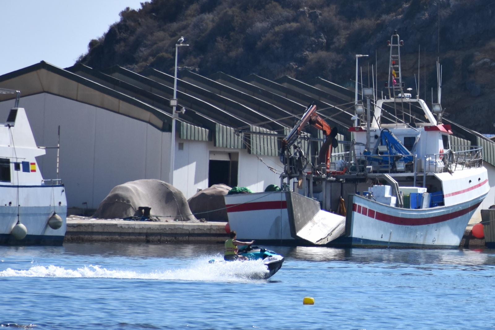 A jet skier passing the fishing trawlers in Puerto de Mazarron harbour
