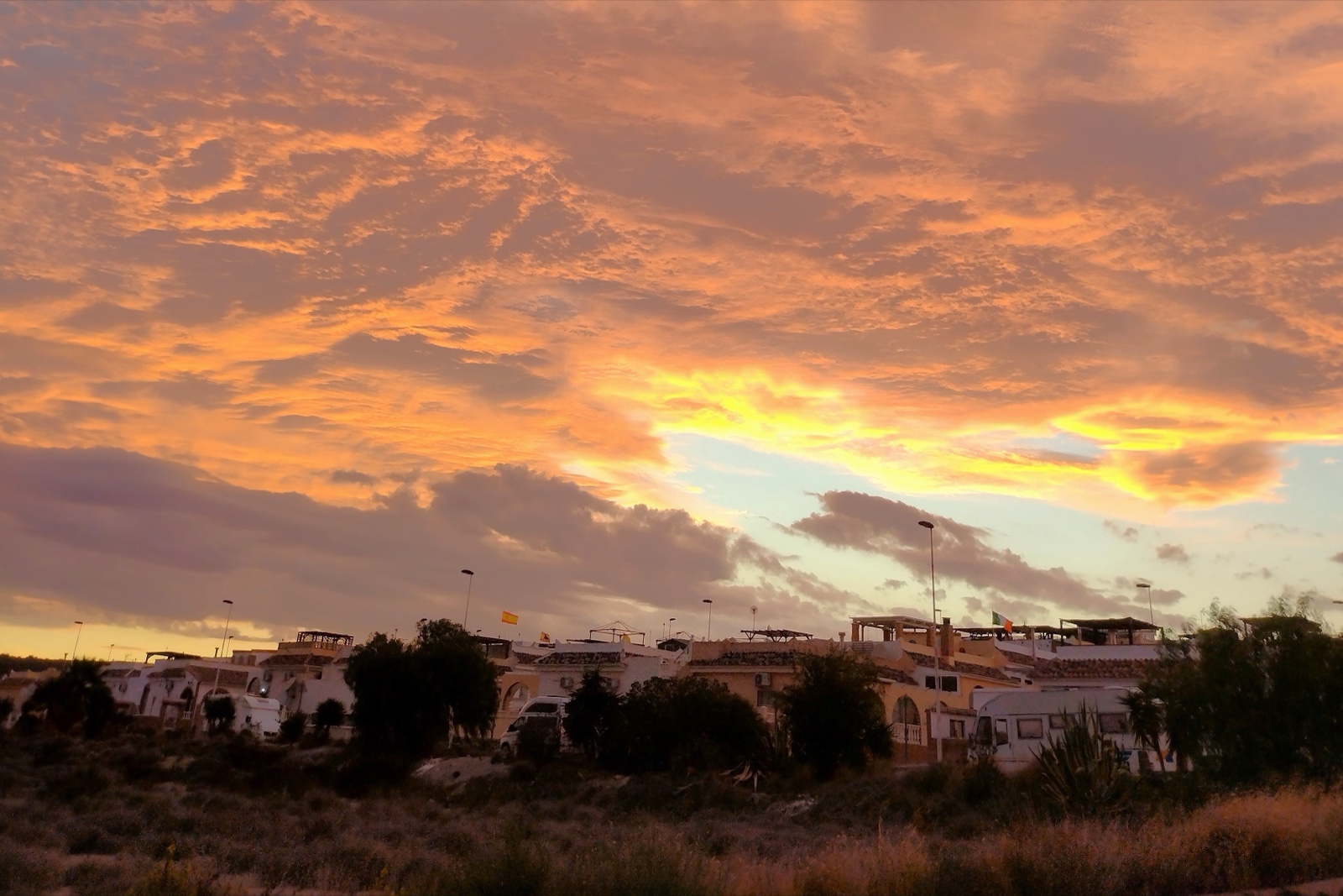 A vivid orange sky on fire at sunset over the Sector D villas, Camposol